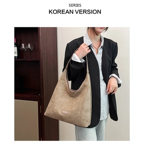 Detail of light brown matte leather tote bag featuring a brand logo plate and wide strap