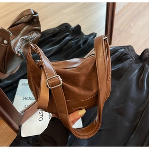Close-up of brown matte suede saddle bag with adjustable strap and metal hardware details