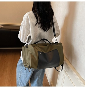 Olive green canvas travel bag with black front zipper pocket and adjustable strap