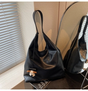 Detail of black faux leather hobo bag texture with a cute plush puppy pendant