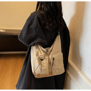 Dettaglio della borsa a tracolla kaki con tasche a coulisse e scomparti con cerniera