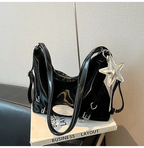 Detail of black patent leather tote bag with silver star pendant and metallic nameplate