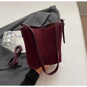 Detailed close-up of burgundy frosted suede bucket bag with wide and thin shoulder straps