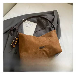 Close-up of brown suede tote bag with leather strap and colorful wooden bead charms