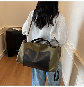 Olive green nylon travel bag with leather accents shown on shoulder for daily commute