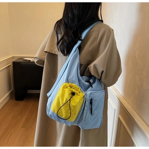 Dettaglio della borsa tote in nylon blu e gialla con multitasche mostrata su una modella