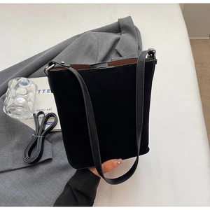 Detail of black matte bucket bag with leather handles and textured microfiber finish