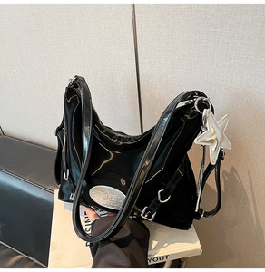 Detailed macro view of black patent leather tote with star charm and silver logo plaque