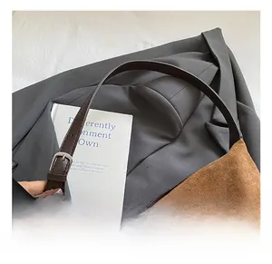 Detail shot of brown suede tote bag featuring dark leather strap and silver metal buckle