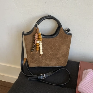 Sac seau marron en daim avec motifs matelassés et ornement de pompon en bois