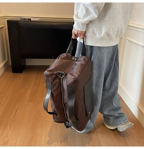 Detail of a large brown travel bag with high-density nylon and durable PU leather handles