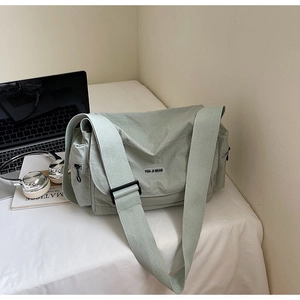 Light green casual nylon messenger bag with wide shoulder strap on desktop
