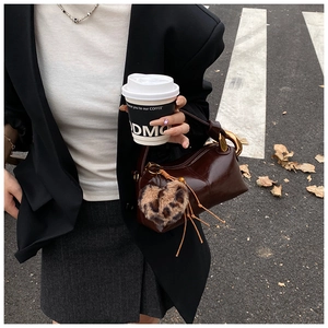 Detail of vintage brown leather pillow bag with a leopard heart charm in street style