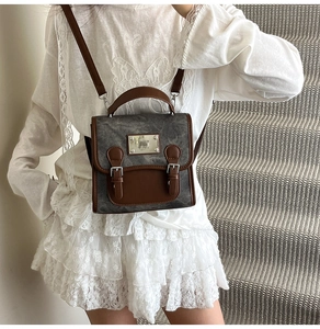 Detail of vintage denim crossbody bag with brown leather straps and metal buckle closure