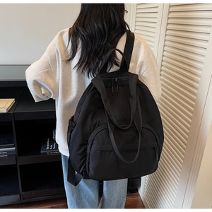 Detail of minimalist black nylon backpack with double handles and front zipper pocket