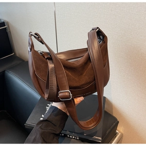 Macro detail of the dark brown matte suede and smooth leather stitching on the saddle bag