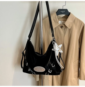 Detail of black patent leather shoulder bag with silver star pendant and metallic hardware