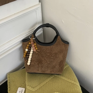 Détail du sac seau en suédine avec bordure contrastée et gland à perles bohème chic