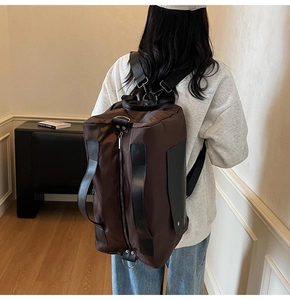 Detail of waterproof nylon travel backpack in dark brown with leather handles and straps