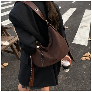 Detail showing the dark coffee suede tote bag with brown shoulder strap and woven lanyard