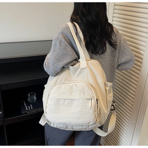 Detailed view of cream canvas tote bag with adjustable shoulder straps and side pockets