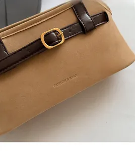 Detail of matte suede texture with decorative faux leather strap and gold buckle