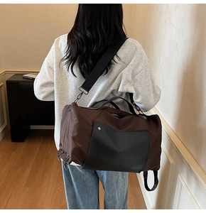 Detail view of large canvas travel bag with brown and black panels and adjustable shoulder strap
