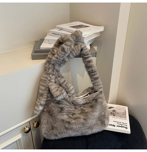 Close-up of taupe faux fur tote bag with a knotted strap on a black chair