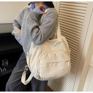 Detailed view of beige nylon tote bag with multiple pockets and adjustable strap