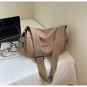 Detail of khaki messenger bag featuring adjustable strap and side pocket on desk