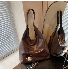 Detailed texture of dark brown leather hobo bag with a cute white puppy plush charm