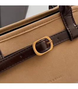 Detail of khaki suede and brown leather texture with vintage gold buckle on a handbag