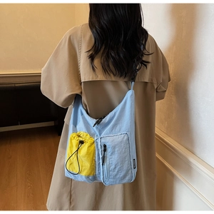 Dettaglio della borsa a tracolla in nylon blu con tasche gialle indossata da una modella