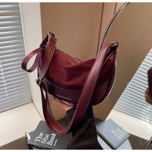 Close-up of burgundy crescent bag featuring suede and smooth leather texture stitching