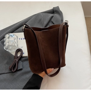 Detailed view of coffee brown suede bucket bag featuring adjustable straps and embossed logo