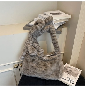 Detail of plush grey faux fur tote bag with stylish knotted handle and soft texture