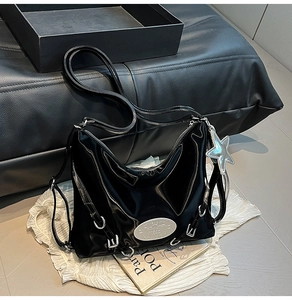Detail of black glossy patent leather hobo bag with silver buckle and star charm