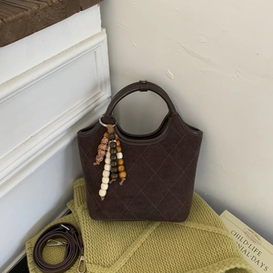 Détail du sac seau en daim marron café avec gland bohème et perles en bois naturel