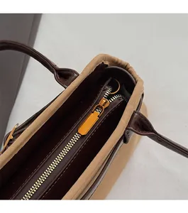 Detailed close-up of smooth gold-tone zipper and premium leather trim on tote bag