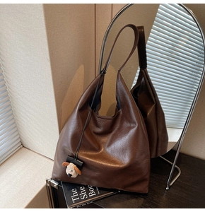 Brown leather tote bag detail with a cute plush puppy charm and minimalist design