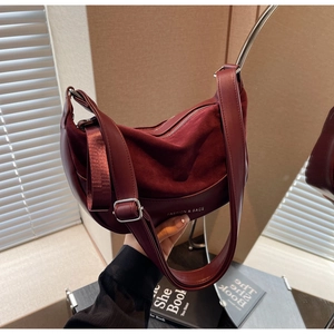 Detail of burgundy saddle bag showing matte leather texture and silver hardware