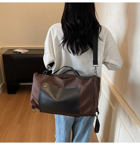 Rear view of a model carrying a large brown canvas travel bag with black leather handles