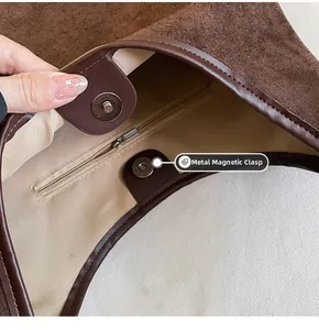 Detail of the magnetic clasp and interior zip pocket on a brown suede tote bag