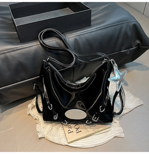 Detail of black patent leather tote bag featuring silver hardware and star pendant