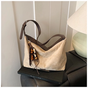 Detail of beige suede hobo bag with dark brown leather strap and wooden bead charm