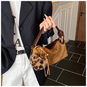 Close-up of brown suede pillow bag with leopard print pom pom and leather tassels
