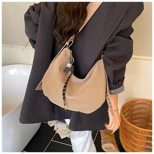 Detail of camel crescent tote bag with wide strap and fashion tag on suede texture