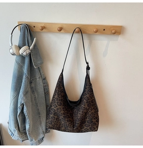 Detail of leopard print tote bag hanging on wooden hook with casual denim jacket