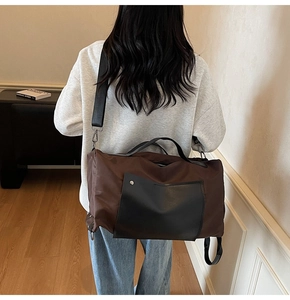Brown canvas travel bag with black leather pockets and adjustable shoulder strap worn by model