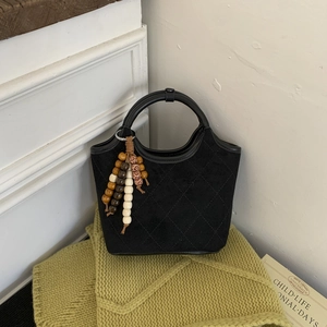 Détail du sac seau noir en daim matelassé avec des breloques décoratives en perles colorées